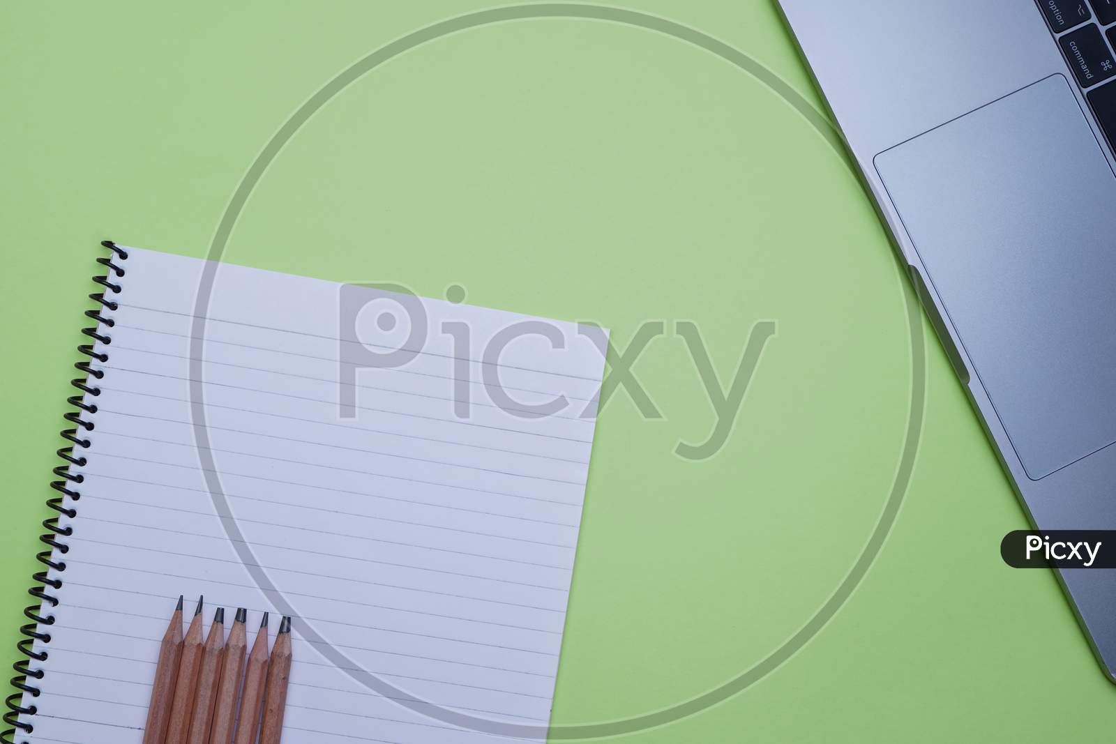Office Top View For Corporate Use. Laptop, Pencils And A Notebook On A Green Background