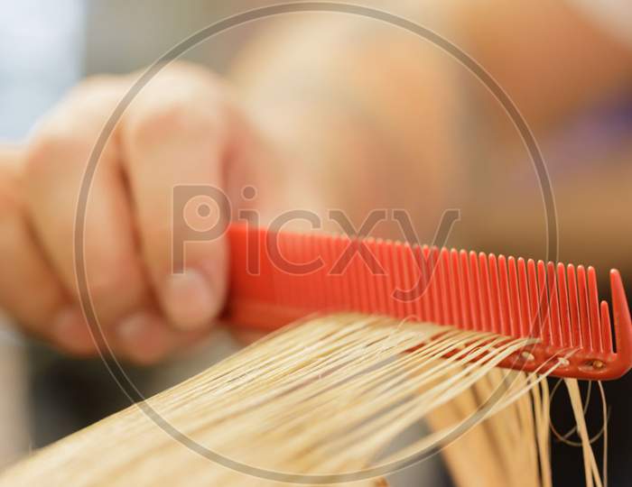 Stylist'S Hand Holds A Comb On Which The Model'S Blonde Strand Of Hair. Selective Focus