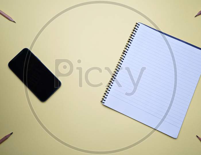 Business, Office, Student, Education Flat Lay, Table Top. Mobile, Phone, Spiral Notebook On Yellow Background