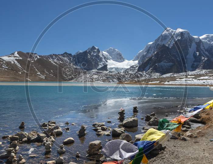 A view of Gurudongmar Lake with Zemu glacier in the background and Tibetan prayer flags in the foreground
