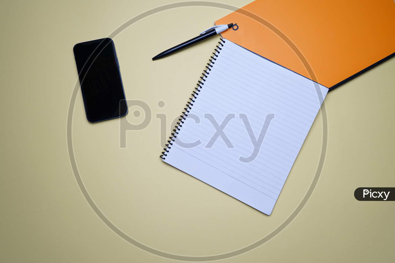 Creative Office, Business Professional Flat Lay, Table Top. Mobile, Phone, Spiral Notebook, Orange Notebook And Pen On Green Background