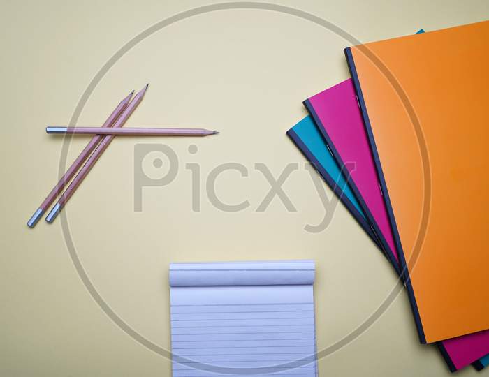 Business, Office, Student, Flat Lay. Cross Pencil, Notepad And Colorful Notebook On Yellow Background