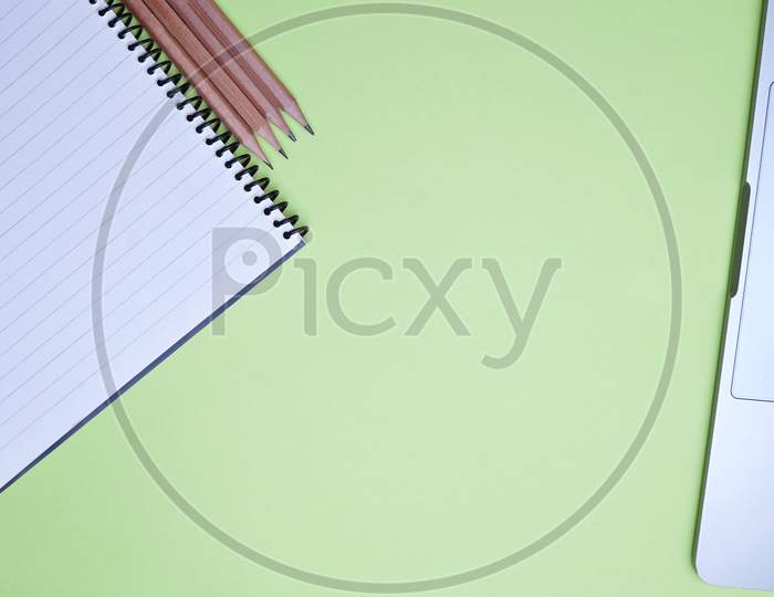 Business, Office, Student, Education Flat Lay, Table Top. Pencil, Spiral Notebook And Laptop On Green Background
