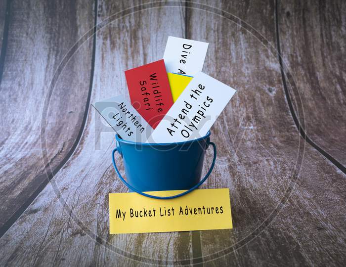 My Bucket List Adventures Written On A Colorful Paper Inside Of A Blue Bucket