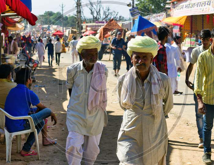Pushkar, India - November 10, 2016: Couple Of Local Rajasthani Old Men Walking In Ethnic Wear With Turban During Famous Pushkar Fair Or Mela Held Annually In Rajasthan State.