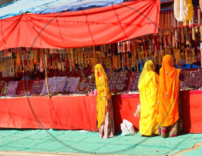Pushkar, India - November 10, 2016: Bunch Of Women In Traditional Hindu Wear Saree Buying Or Shopping Jewelery Items In The Commercial Street Of Pushkar Fair In The State Of Rajasthan