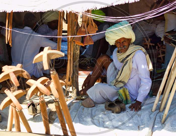 Pushkar, India - November 10, 2016: A Rajasthani Man With Turban Selling Camel Related Wooden Items In The Commercial Market Of Pushkar Fair Or Mela In The State Of Rajasthan