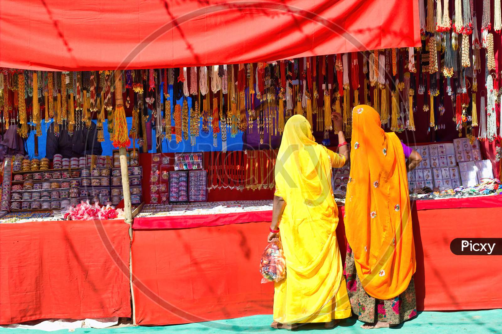 Couple Of Unidentified Women In Traditional Hindu Wear Saree Buying Or Shopping Jewelery Items In The Commercial Street Of Pushkar Fair In State Of Rajasthan, India. Colorful Indian Culture Concept