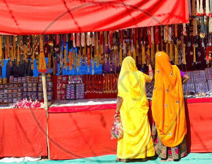 Couple Of Unidentified Women In Traditional Hindu Wear Saree Buying Or Shopping Jewelery Items In The Commercial Street Of Pushkar Fair In State Of Rajasthan, India. Colorful Indian Culture Concept