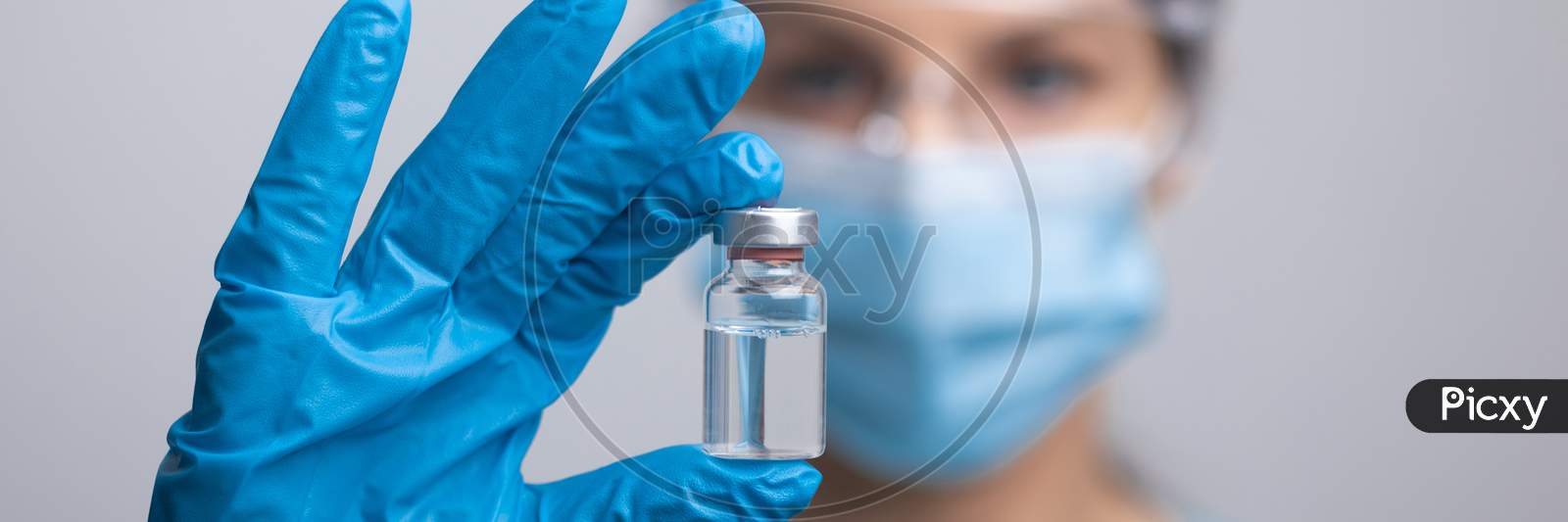 Doctor Scientis In Protective Gloves And Mask Holding Glass Vial With Injection Liquid. Vaccination Against Influenza And Coronavirus.