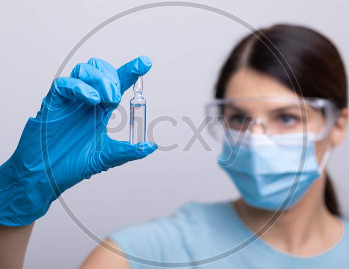 Doctor In Protective Gloves And Mask Holding Glass Vial With Injection Liquid. Vaccination Against Influenza And Coronavirus.