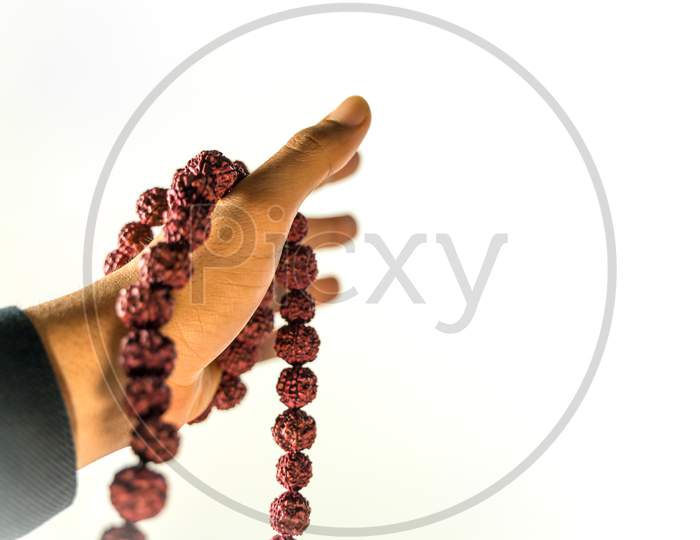 Image Of Prayer Beads In Hand. Male Hand Holding Rosary, Praying To God On White Background, Religious Spirituality. Man Holding Rosary Beads And Meditating. Religious Concept