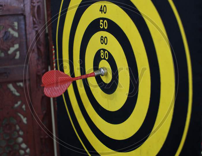 Red dart arrow hitting in the target center of dartboard with nice back ground. Business success concept shown with Dart and Dartboard. Marketing Aim concept. Symbolic representation of achieving goal in business.