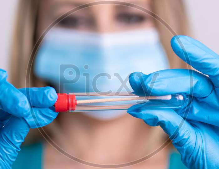 Nurse With Facemask Holding Coronavirus Covid-19 Swab Test Kit, Ppe Protective Mask And Gloves, Tube For Taking Op Np Patient Specimen Sample, Pcr Dna Rna Testing Protocol Process