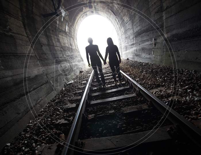 Couple Walking Together Through A Railway Tunnel