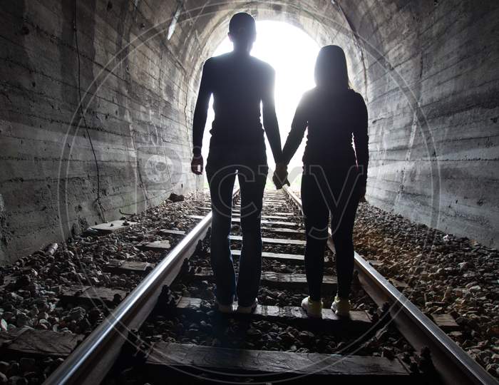 Couple Walking Together Through A Railway Tunnel