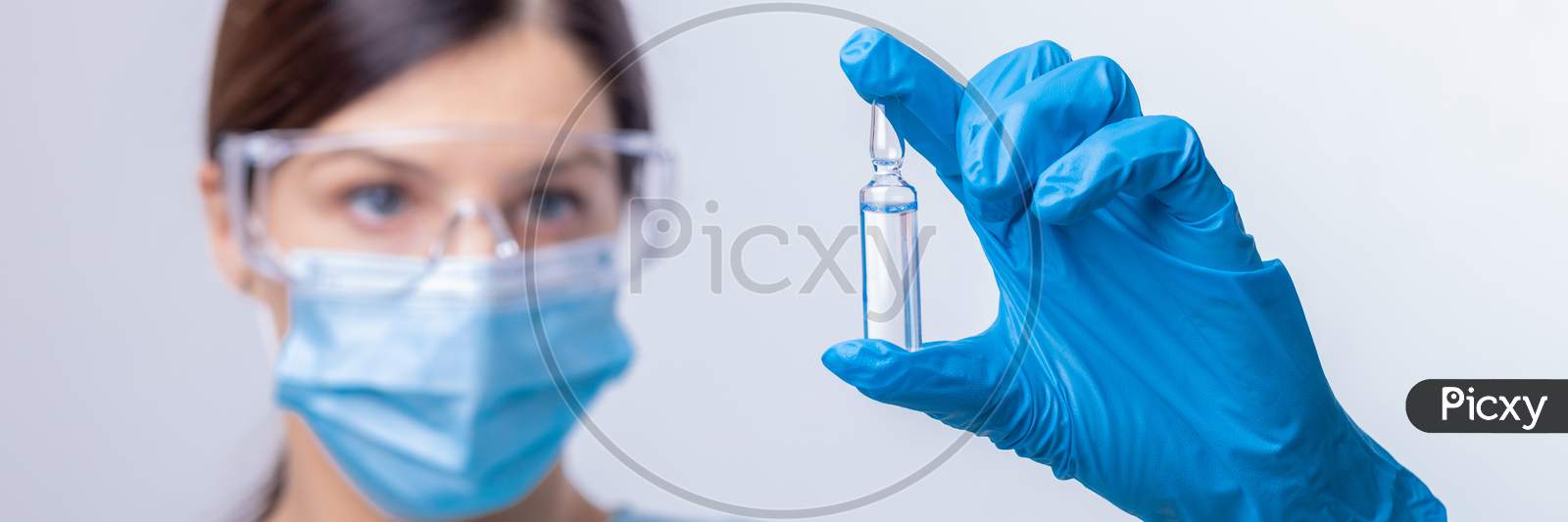Doctor In Protective Gloves And Mask Holding Glass Vial With Injection Liquid. Vaccination Against Influenza And Coronavirus.