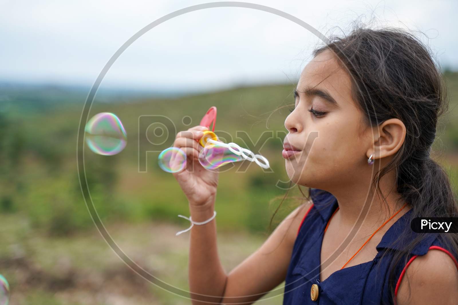 Young Girl Kid Playing By Blowing Soap Water Bubbles - Conept Of Playful Chidlren During Holiday Vacation.
