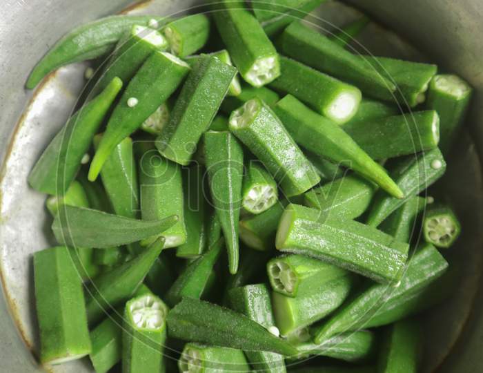 Lots of chopped green raw Okra into a aluminum bowl before cooking at home in Dhaka, Bangladesh
