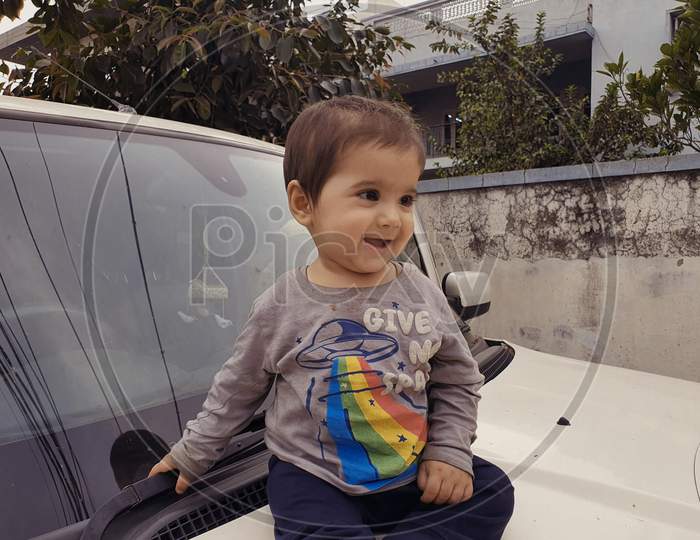 Kid Smiling Is In Car Seat. A Small Chile Of Kashmir Asian Origin.