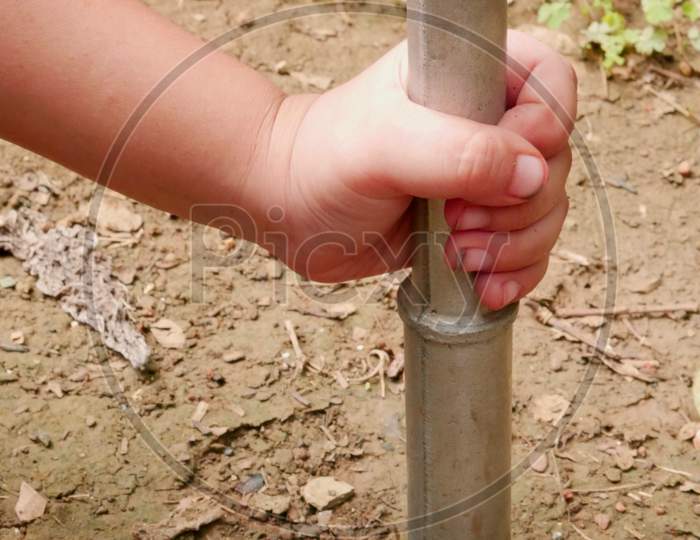 Kid Hand Holding Iron Construction Tools While Hitting Soil Land.