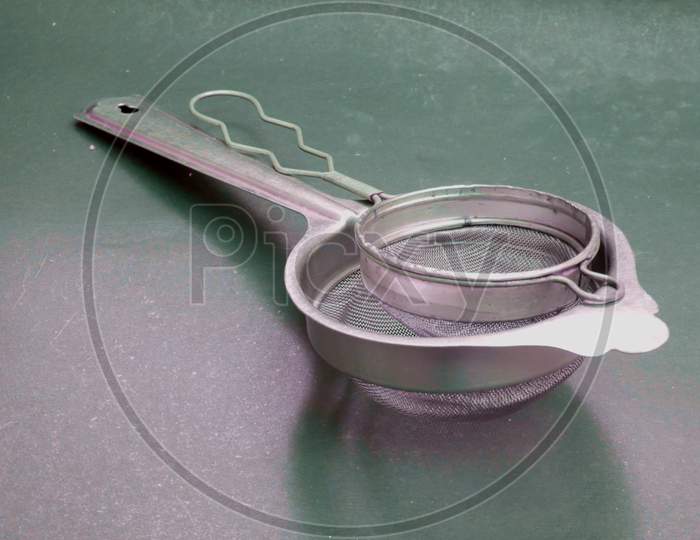 Double Stainless Steel Tea Filter Kept Together On Gray Backdrop, Kitchen Cutlery Product Image.