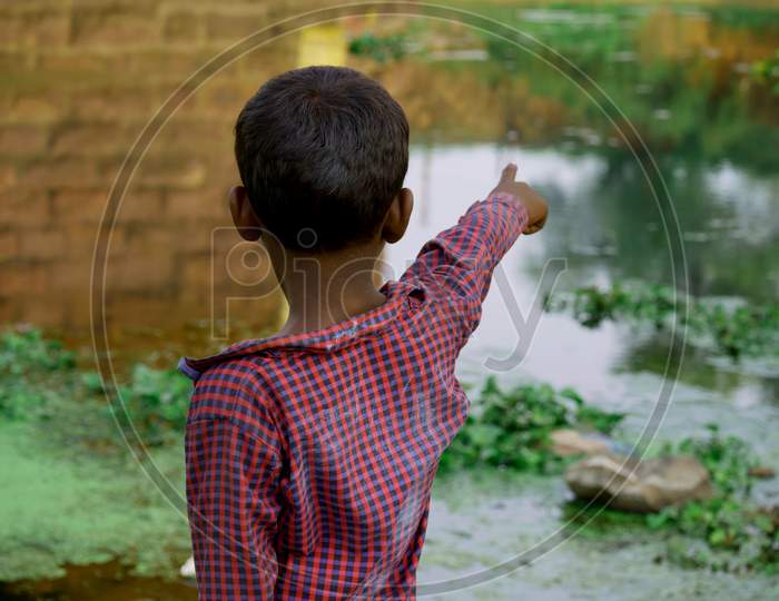 A Asian Boy Pointing Hand Towards Lake Side, Kids Lifestyle Concept Image