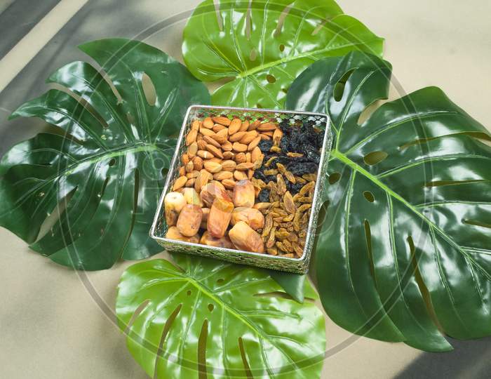 Organic Healthy Food In Bowl On Tropical Leaves,Different Dry Fruits Almonds Dates Dry Black Raisins