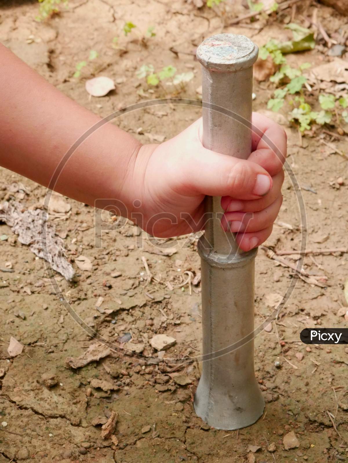 Kid Hand Holding Iron Construction Tools While Hitting Soil Land.