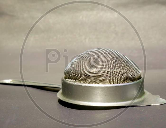 Stainless Steel Tea Filter Isolated On Gray Backdrop, Kitchen Cutlery Product Image.