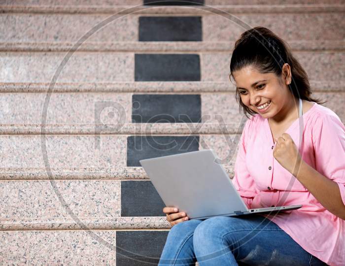 A  Young Happy girl showing thumbs up towards the camera with laptop