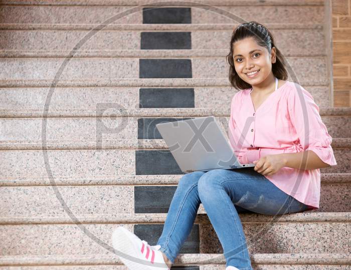 A  Young Happy girl showing thumbs up towards the camera with laptop