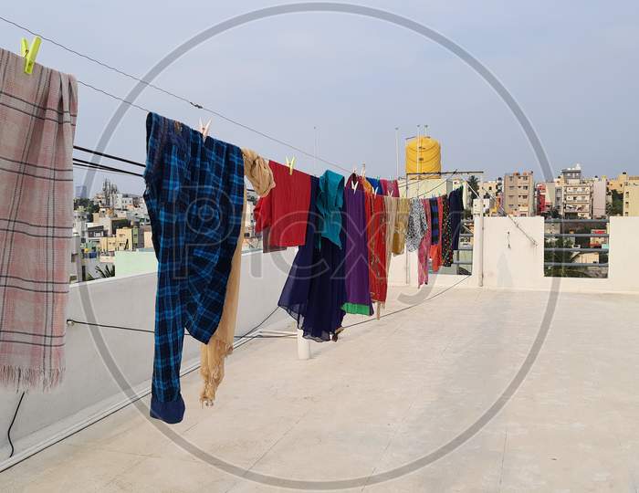 Washed Wet Cloths Hanged In A Terrace With Thread And Plastic Clips At The Building Top