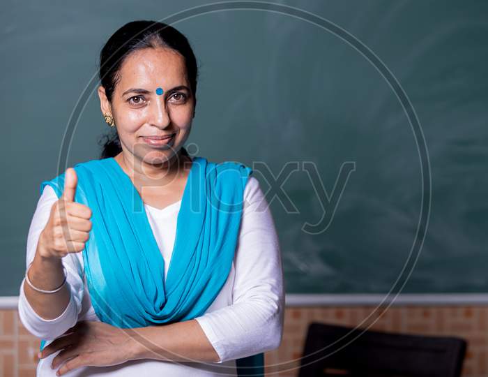 A  indian teacher showing thumbs up toward the camera