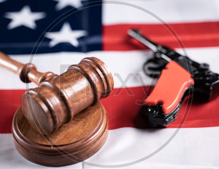 Concept Showing Of Us Or American Gun Laws With Judge Gavel And Vintage Pistol On American Flag.