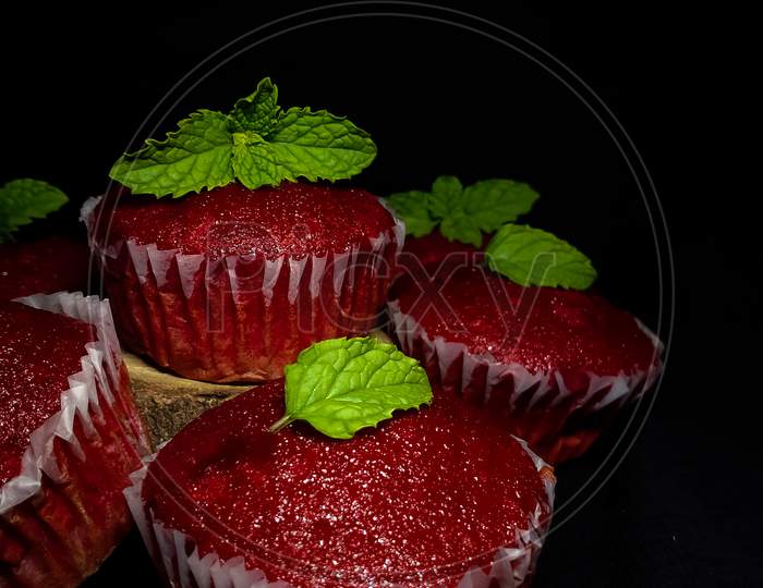 Closeup of Delicious Red Velvet cupcakes or muffins decorated with mint on top.