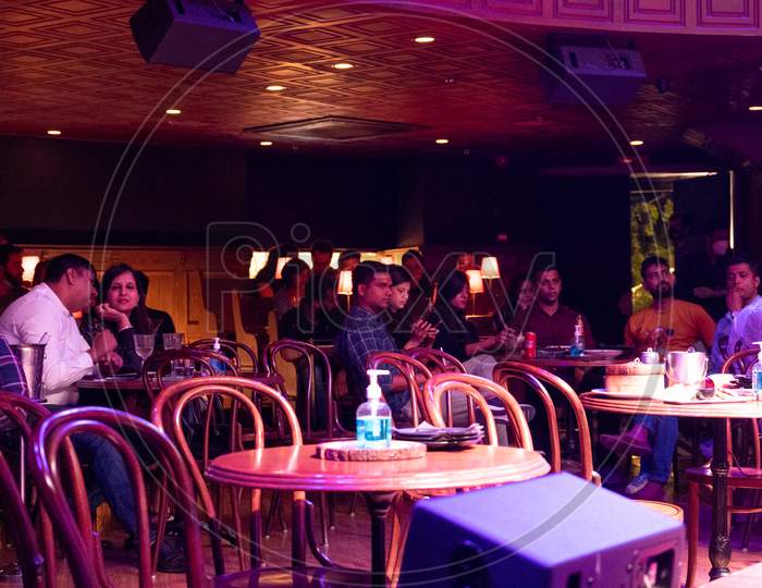 Indian Audience Sitting In A Colorfully Lit Bar Pub Club Restaurant Disco During A Live Music Performance As Things Open Up Post The Covid19 Coronavirus Pandemic