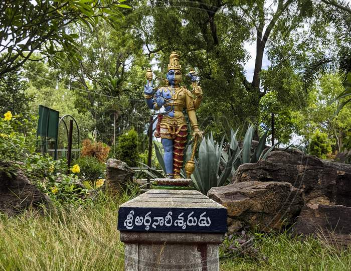 Long View of Lord Shiva-Parvathi Ardanarishwara Avatar idol in Natural Rock Garden in Vertical