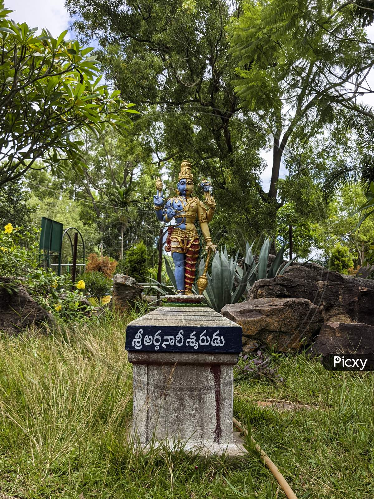 Long View of Lord Shiva-Parvathi Ardanarishwara Avatar idol in Natural Rock Garden in Vertical