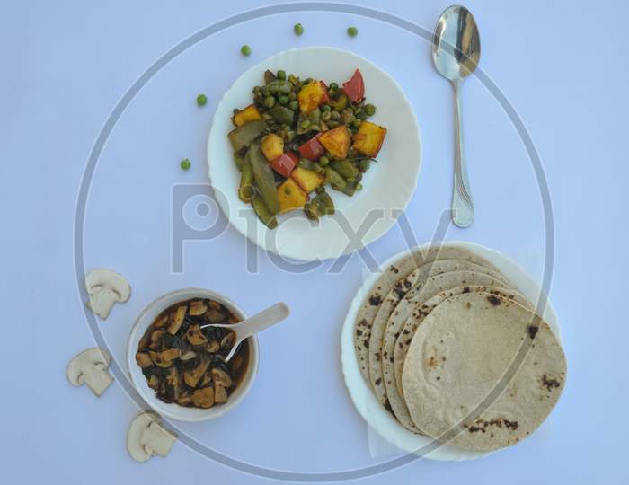 Overhead view of matar paneer veg, mashroom soup and roti (Indian food) over white background, with copy space