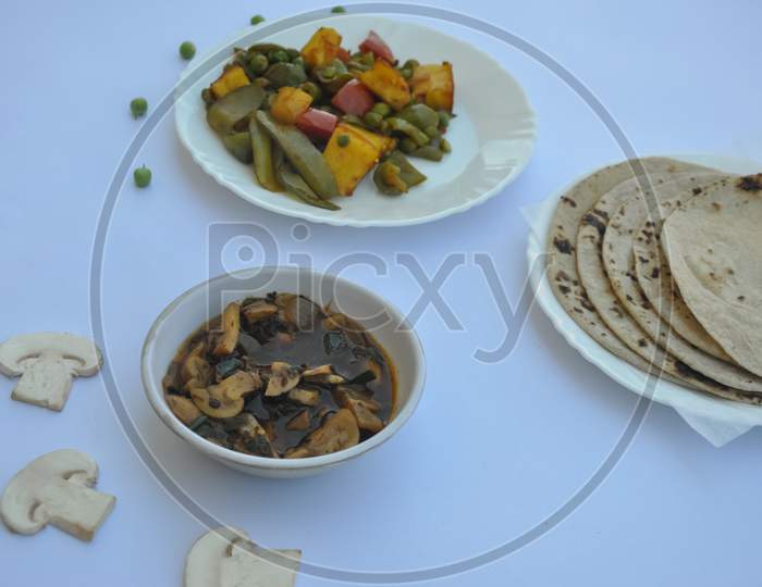 Flat lay of matar paneer veg, mashroom soup and roti (Indian food).