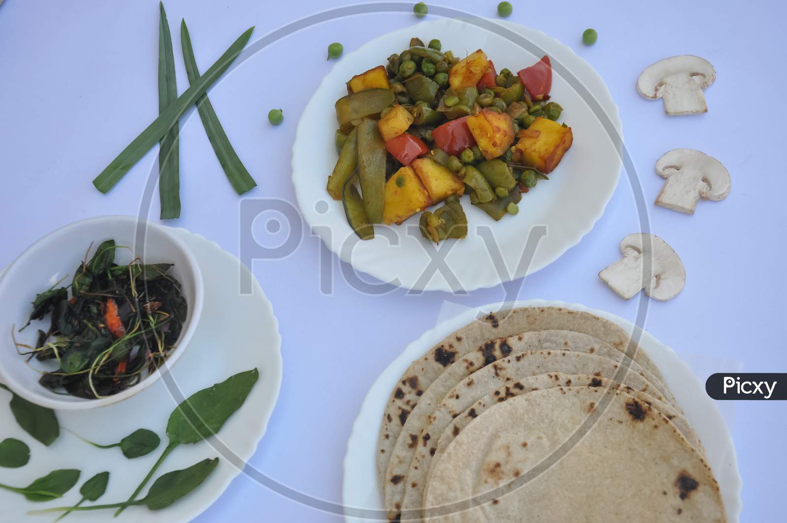 Indian Food: Flat lay of matar paneer mix veg, saag (greens) and roti (chapati) isolated over white background