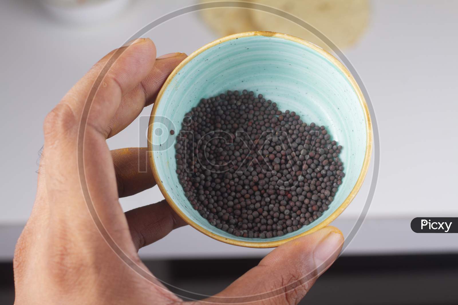 Mustard Seeds Bowl In Hand Isolated On Light Background.