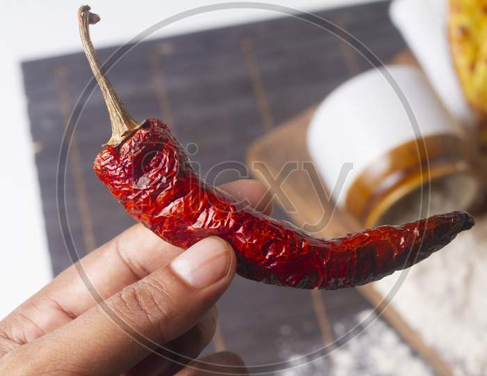 Dry Red Chili In Hand Isolated On Light Background