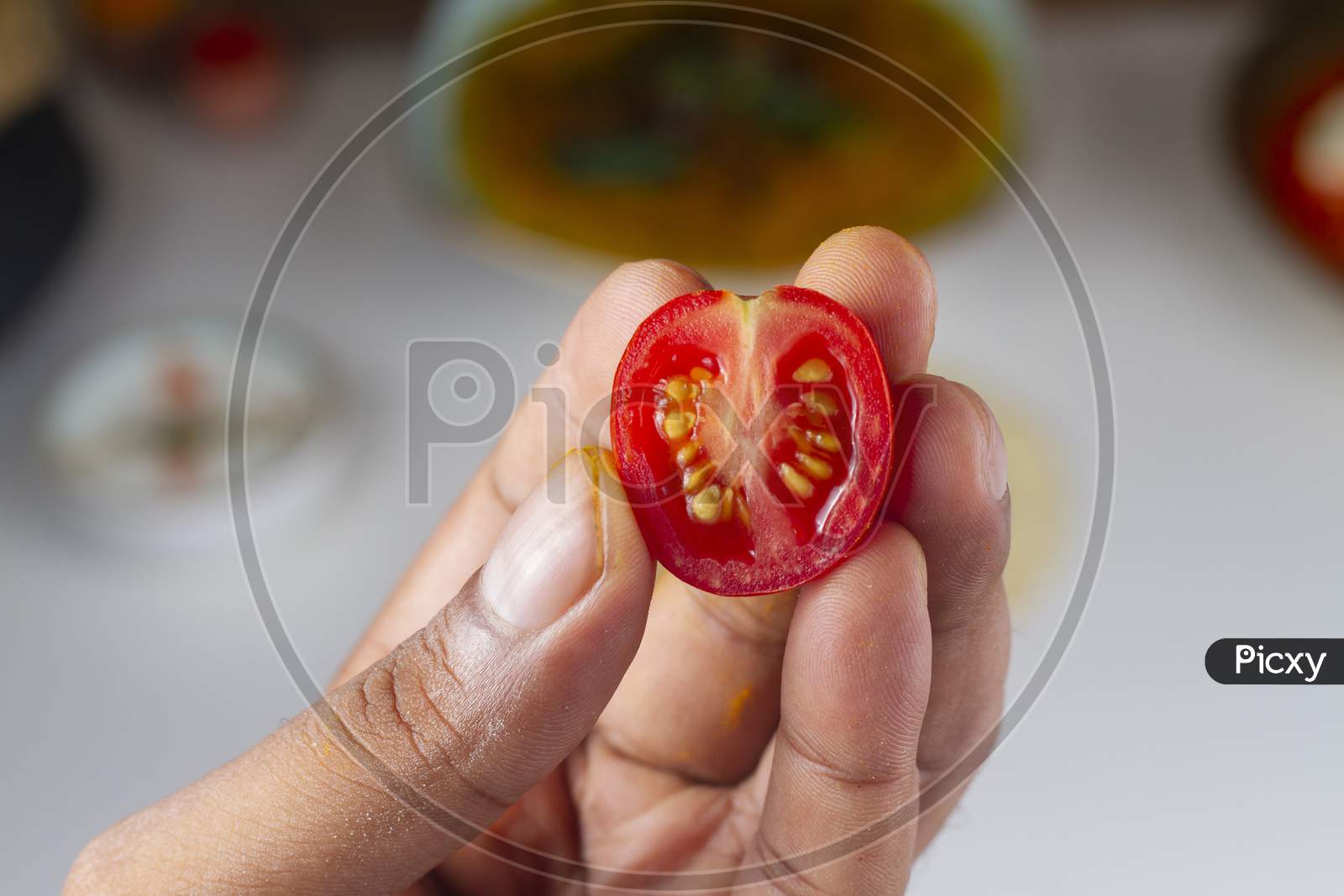 Cut Cherry Tomato In Hand Isolated On Light Background