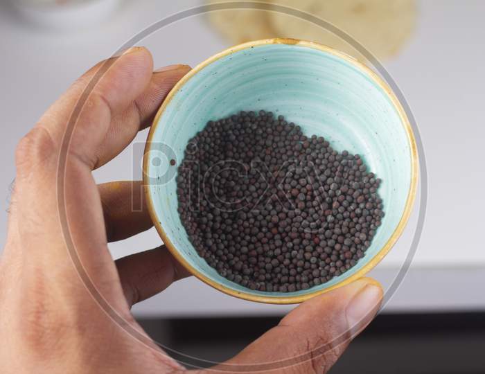 Mustard Seeds Bowl In Hand Isolated On Light Background.