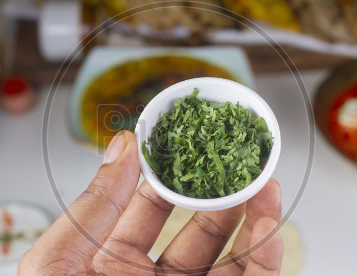 A Person Holding A Chopped Cilantro Bowl In Hand Isolated On Light Background.