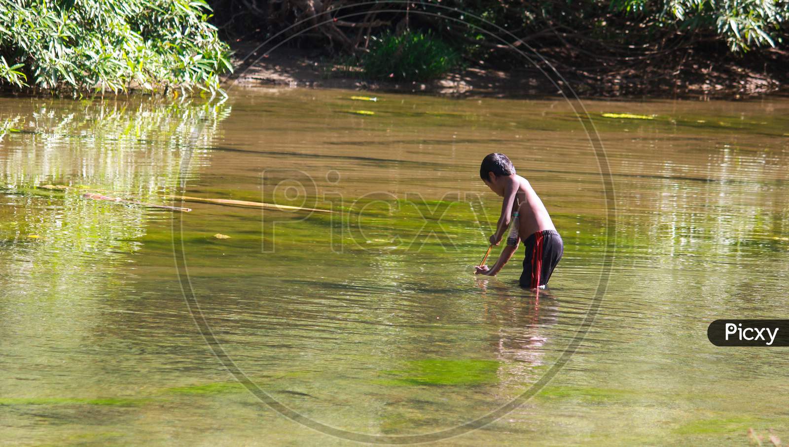 little aboriginal boy catching fish into river in traditional way in Bandarban, Bangladesh