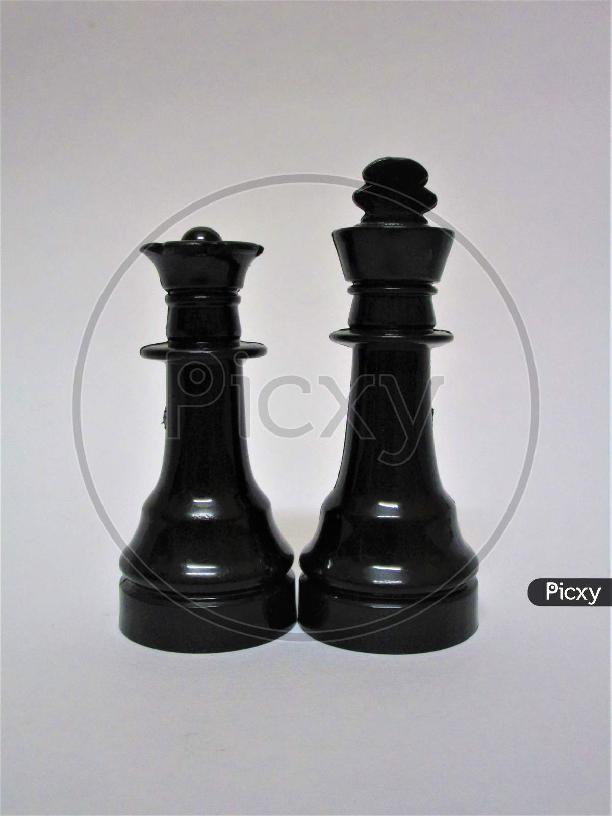 Chess pieces queen and king together on a white background.
