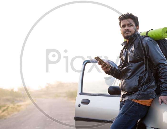 Young Traveler Using Mobile While Waiting Outside The Car With Backpack - Cocept Of Car Failure Or Broken During Travel On Raodside.